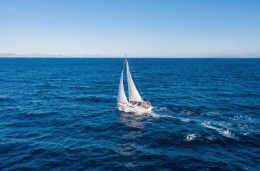 Sailing. Sailboat with open white sails, blue sky and sea, windy day. Summer vacation in Mediterranean sea Greece