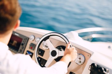 Man in a white shirt is driving a white motor boat. Close-up. High quality photo